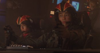 Movie still from “Godzilla vs. Mechagodzilla II” (1993), directed by Kazuki Ômori – Two men in helmets are looking at a cell phone; Medium shot, Low angle