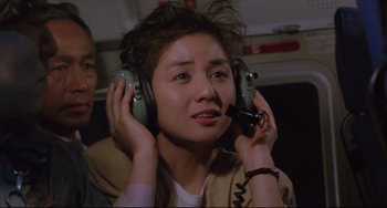Movie still from “Godzilla vs. Mechagodzilla II” (1993), directed by Kazuki Ômori – A person with headphones on holding a cell phone to their ear; Close Up shot, Low angle