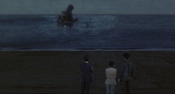 Movie still from “Godzilla vs. Mechagodzilla II” (1993), directed by Kazuki Ômori – Two men and a woman standing in the water watching a monster in the water; Extreme Wide shot, Over the shoulder angle