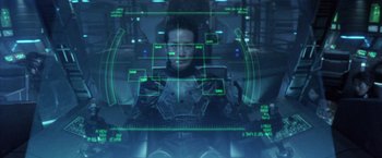 Movie still from “Godzilla: Final Wars” (2004), directed by Koji Hashimoto – A man is sitting in a chair in front of a computer screen; Medium shot, High angle