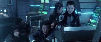 Movie still from “Godzilla: Final Wars” (2004), directed by Koji Hashimoto – A group of people sitting in a room; Medium shot, Over the shoulder angle