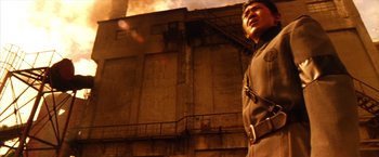 Movie still from “Godzilla: Final Wars” (2004), directed by Koji Hashimoto – A man standing in front of a building on fire; Medium shot, Low angle