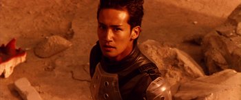 Movie still from “Godzilla: Final Wars” (2004), directed by Koji Hashimoto – A man wearing a black and silver outfit; Close Up shot, High angle
