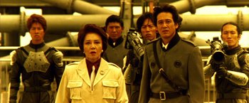 Movie still from “Godzilla: Final Wars” (2004), directed by Koji Hashimoto – A group of men and a woman standing next to each other; Medium shot, Low angle