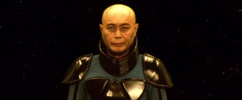 Movie still from “Godzilla: Final Wars” (2004), directed by Koji Hashimoto – A bald man in a blue and black outfit; Close Up shot, Low angle