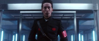 Movie still from “Godzilla: Final Wars” (2004), directed by Koji Hashimoto – A man in a black uniform with a red armband; Close Up shot, Low angle