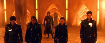 Movie still from “Godzilla: Final Wars” (2004), directed by Koji Hashimoto – A group of people in shiny clothing walk through an archway; Wide shot, Low angle