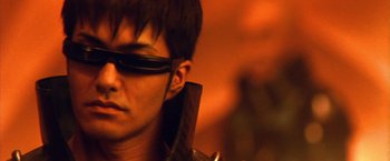 Movie still from “Godzilla: Final Wars” (2004), directed by Koji Hashimoto – A young man wearing a pair of sunglasses and holding a sword; Close Up shot, Low angle