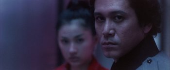 Movie still from “Godzilla: Final Wars” (2004), directed by Koji Hashimoto – A man and a woman are looking at the camera; Close Up shot, Low angle