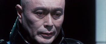 Movie still from “Godzilla: Final Wars” (2004), directed by Koji Hashimoto – A bald man's face in a dark room; Close Up shot, High angle