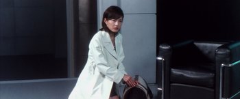 Movie still from “Godzilla: Final Wars” (2004), directed by Koji Hashimoto – A woman in a white coat standing next to a mailbox; Medium shot, High angle