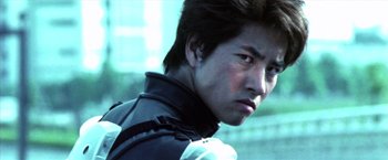 Movie still from “Godzilla: Final Wars” (2004), directed by Koji Hashimoto – A young man in a motorcycle jacket looking to his left; Close Up shot, Low angle
