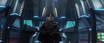 Movie still from “Godzilla: Final Wars” (2004), directed by Koji Hashimoto – A man in a uniform sitting in a chair; Medium shot, Low angle