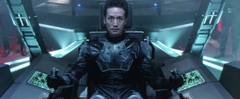 Movie still from “Godzilla: Final Wars” (2004), directed by Koji Hashimoto – A man sitting in a chair in a room; Medium shot, Low angle