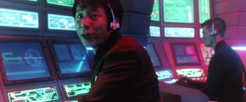 Movie still from “Godzilla: Final Wars” (2004), directed by Koji Hashimoto – A man wearing a headset in a room with a lot of lights; Medium shot, Low angle