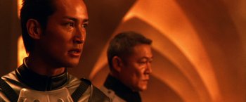 Movie still from “Godzilla: Final Wars” (2004), directed by Koji Hashimoto – Two men standing next to each other in front of an orange wall; Close Up shot, Low angle