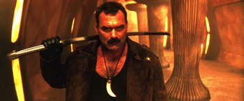 Movie still from “Godzilla: Final Wars” (2004), directed by Koji Hashimoto – A man in a leather jacket holding a knife in one hand and an arrow in the other; Close Up shot, Low angle