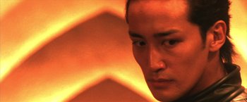 Movie still from “Godzilla: Final Wars” (2004), directed by Koji Hashimoto – A man's face in front of an orange background; Close Up shot, Low angle