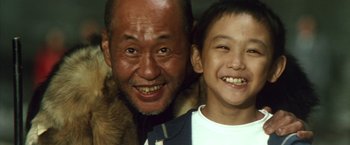 Movie still from “Godzilla: Final Wars” (2004), directed by Koji Hashimoto – An older man and a young boy smiling for the camera; Close Up shot, Low angle