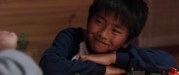 Movie still from “Godzilla: Tokyo S.O.S.” (2003), directed by Takao Okawara – A young asian boy smiling for the camera with his arms crossed; Close Up shot, High angle