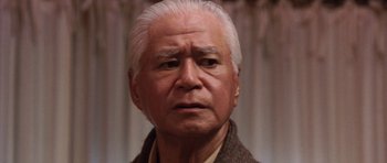 Movie still from “Godzilla: Tokyo S.O.S.” (2003), directed by Takao Okawara – An older man with white hair wearing a brown jacket; Close Up shot, Low angle