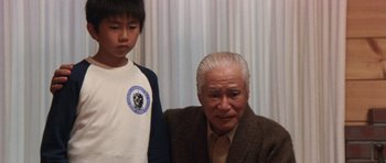 Movie still from “Godzilla: Tokyo S.O.S.” (2003), directed by Takao Okawara – An older man and a young boy standing next to each other; Medium shot, Low angle