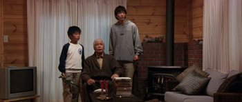 Movie still from “Godzilla: Tokyo S.O.S.” (2003), directed by Takao Okawara – Three people standing in front of a fire place; Wide shot, Low angle