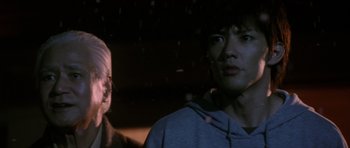 Movie still from “Godzilla: Tokyo S.O.S.” (2003), directed by Takao Okawara – A man standing next to another man in the dark; Close Up shot, Low angle