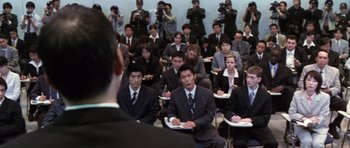 Movie still from “Godzilla: Tokyo S.O.S.” (2003), directed by Takao Okawara – A group of people in suits sitting in front of a camera; Wide shot, High angle