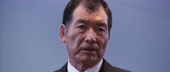 Movie still from “Godzilla: Tokyo S.O.S.” (2003), directed by Takao Okawara – An older asian man wearing a suit and tie; Close Up shot, Low angle