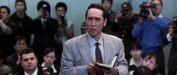 Movie still from “Godzilla: Tokyo S.O.S.” (2003), directed by Takao Okawara – A man in a suit and tie holding a notebook; Close Up shot, Low angle