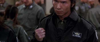 Movie still from “Godzilla: Tokyo S.O.S.” (2003), directed by Takao Okawara – A man in a black jacket holding a pen in his hand; Close Up shot, High angle