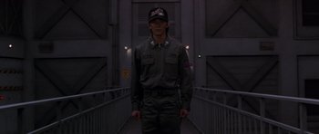 Movie still from “Godzilla: Tokyo S.O.S.” (2003), directed by Takao Okawara – A man standing on a bridge wearing a hat; Medium shot, Low angle