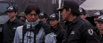 Movie still from “Godzilla: Tokyo S.O.S.” (2003), directed by Takao Okawara – A group of people standing next to each other wearing hats; Close Up shot, Over the shoulder angle