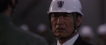 Movie still from “Godzilla: Tokyo S.O.S.” (2003), directed by Takao Okawara – An older man in a suit wearing a white helmet; Close Up shot, Low angle