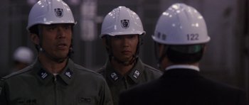 Movie still from “Godzilla: Tokyo S.O.S.” (2003), directed by Takao Okawara – A group of men wearing hard hats talking to each other; Close Up shot, Over the shoulder angle