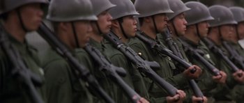 Movie still from “Godzilla: Tokyo S.O.S.” (2003), directed by Takao Okawara – A group of men in green uniforms and helmets holding guns; Medium shot, High angle