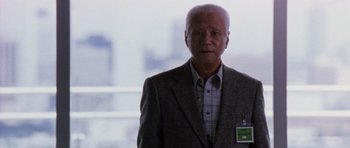 Movie still from “Godzilla: Tokyo S.O.S.” (2003), directed by Takao Okawara – An older man wearing a suit and tie; Medium shot, Low angle