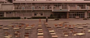 Movie still from “Godzilla: Tokyo S.O.S.” (2003), directed by Takao Okawara – A man standing in front of rows of desks in an empty school yard; Extreme Wide shot, High angle