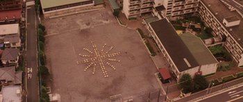 Movie still from “Godzilla: Tokyo S.O.S.” (2003), directed by Takao Okawara – An aerial view of a building and a parking lot; Extreme Wide shot, Overhead angle