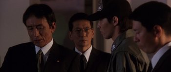 Movie still from “Godzilla: Tokyo S.O.S.” (2003), directed by Takao Okawara – A group of men standing next to each other in a room; Close Up shot, Over the shoulder angle