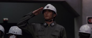 Movie still from “Godzilla: Tokyo S.O.S.” (2003), directed by Takao Okawara – A man in a uniform saluting with a helmet on his head; Close Up shot, Low angle