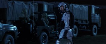 Movie still from “Godzilla: Tokyo S.O.S.” (2003), directed by Takao Okawara – A man in a space suit standing in front of an army vehicle; Medium shot, Over the shoulder angle