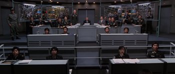 Movie still from “Godzilla: Tokyo S.O.S.” (2003), directed by Takao Okawara – A group of people sitting at desks in a room; Wide shot, High angle