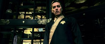 Movie still from “Goemon” (2009), directed by Kazuaki Kiriya – A man in a black and gold outfit standing in front of a wall; Medium shot, Low angle