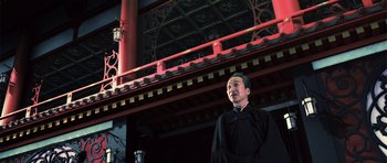 Movie still from “Goemon” (2009), directed by Kazuaki Kiriya – A man in a black robe standing in front of a red building; Medium shot, Low angle