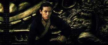 Movie still from “Goemon” (2009), directed by Kazuaki Kiriya – A man in a black and gold outfit sitting in front of a wall; Close Up shot, Low angle