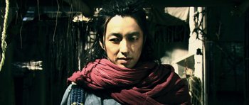 Movie still from “Goemon” (2009), directed by Kazuaki Kiriya – A man with long black hair wearing a red scarf; Close Up shot, Low angle