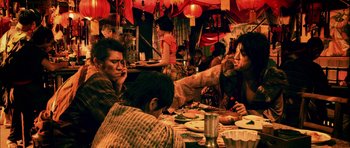 Movie still from “Goemon” (2009), directed by Kazuaki Kiriya – A group of people sitting at a table eating food; Medium shot, Over the shoulder angle