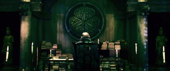 Movie still from “Goemon” (2009), directed by Kazuaki Kiriya – A man sitting at a desk in front of books; Wide shot, Over the shoulder angle